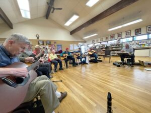 District 8 September Meeting - members playing guitar, fiddle, harmonica, and mandolin